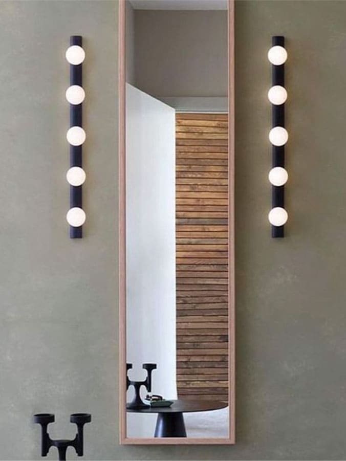 Illuminazione lampada da parete in metallo con 5 lampadine stile camerino degli attori Astro Light modello Cabaret 5 montata accanto ad uno specchio sulla parete all'interno di un bagno